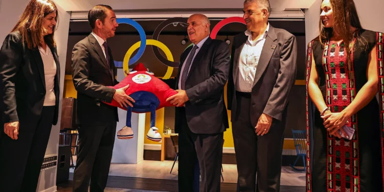 El presidente de la Asociación Palestina de Fútbol y del Comité Olímpico Palestino, Jibril Rajoub (centro), y el cónsul general de Francia en Jerusalén, Nicolas Kassianides (segundo de la izquierda), intercambian regalos, flanqueados por el ministro de Asuntos Exteriores de la Autoridad Palestina, Varsen Aghabekian (izq.), y la nadadora palestino-estadounidense Valerie Rose Tarazi, durante una ceremonia de despedida de la delegación palestina a los próximos Juegos Olímpicos de París 2024, en la ciudad cisjordana de Ramallah, el 14 de julio de 2024. (Zain Jaafar/AFP)