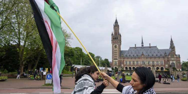 Dos manifestantes ondean la bandera palestina en el exterior del Palacio de la Paz, que alberga la Corte Internacional de Justicia, o Tribunal Mundial, en La Haya, Países Bajos, el 24 de mayo de 2024. (AP/Peter Dejong)