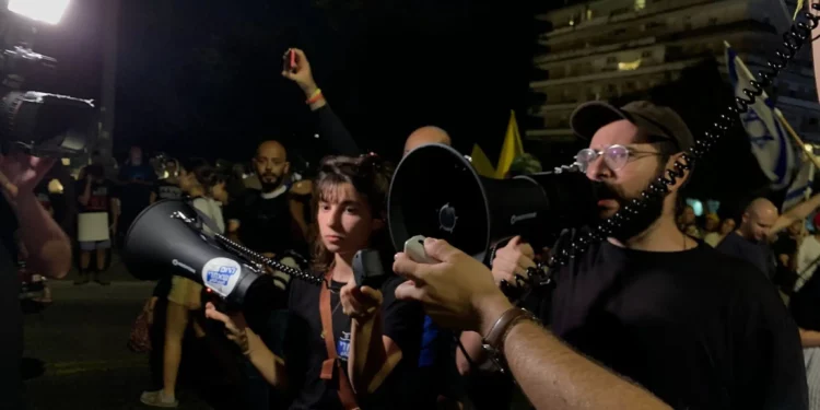 El activista antigubernamental Tomer Lev da un discurso improvisado en el que ordena a los manifestantes marchar en silencio hacia la residencia del primer ministro Benjamin Netanyahu, en vista del mortal ataque de Hezbolá en los Altos del Golán, el 27 de julio de 2024. (Charlie Summers/Times of Israel)