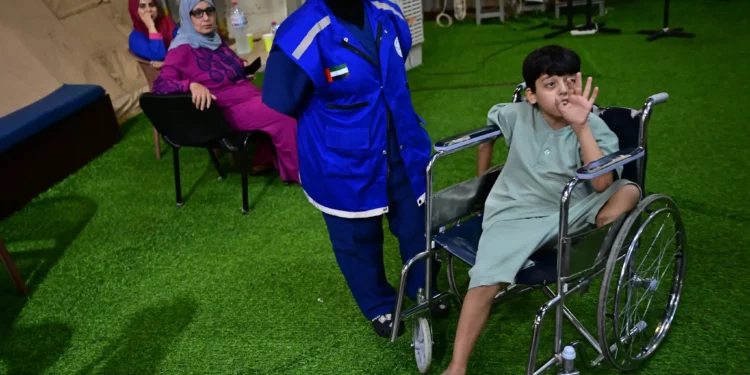 Un joven palestino amputado evacuado de la Franja de Gaza se sienta en una silla de ruedas mientras un médico observa a bordo de un hospital flotante emiratí en el puerto egipcio de Al-Arish el 4 de julio de 2024, durante una gira de prensa organizada. (Foto de Giuseppe CACACE / AFP)