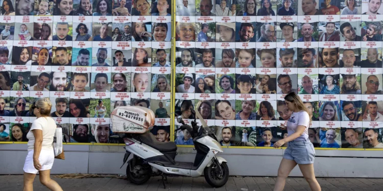 La gente pasa junto a carteles de israelíes tomados como rehenes por Hamás en Gaza desde el 7 de octubre, en Tel Aviv, el 11 de agosto de 2024. (Oren ZIV / AFP)