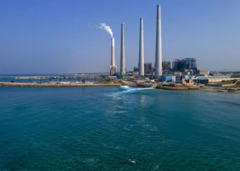 Un practicante de paddle surf pasa por la central eléctrica de Orot Rabin, cerca de Hadera, en el centro de Israel, el 6 de noviembre de 2022. (Foto AP/Ariel Schalit)