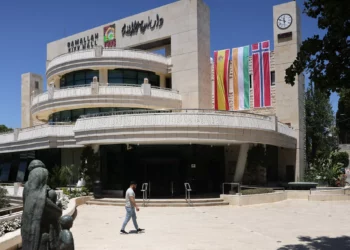 Un hombre camina frente al edificio del ayuntamiento de Ramallah, en Judea y Samaria, el 24 de mayo de 2024, adornado con banderas de España, Irlanda y Noruega. (Ahmad Gharabli/ AFP)