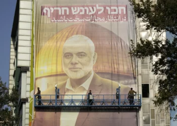 Trabajadores iraníes instalan una enorme pancarta en una pared que muestra un retrato del líder del grupo terrorista Hamás, Ismail Haniyeh, y el santuario islámico Cúpula de la Roca en la cima del Monte del Templo en Jerusalén con un cartel que dice en farsi y hebreo: “Esperen un castigo severo”, en la Plaza Palestina en Teherán, Irán, el 31 de julio de 2024. Haniyeh fue asesinado en la ciudad horas antes. (Foto AP/Vahid Salemi)