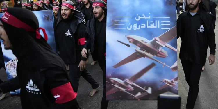 Miembros del Hezbolá, respaldado por Irán, caminan descalzos mientras llevan un cartel que muestra drones del Hezbolá que dice, en árabe, “Estamos llegando”, durante el día sagrado de Ashura en el suburbio sur de Beirut, Líbano, el 9 de agosto de 2022. (Foto AP/Hussein Malla, Archivo)