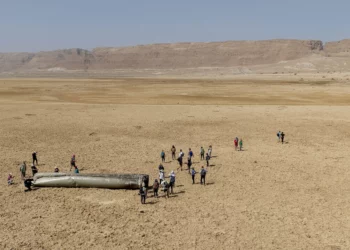 La gente se reúne alrededor de un componente de un misil balístico interceptado disparado por Irán el 14 de abril de 2024 que cayó cerca del mar muerto, el 20 de abril de 2024. (AP/Itamar Grinberg)