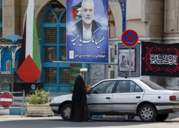 Un clérigo se encuentra junto a un cartel que representa al líder del grupo terrorista Hamás asesinado, Ismail Haniyeh, en la plaza Palestina de Teherán, el 8 de agosto de 2024 (Foto de AFP)