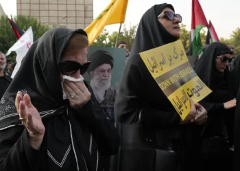 Un manifestante llora mientras otros sostienen un cartel antiisraelí y un póster del líder supremo iraní, el ayatolá Ali Jamenei, en una manifestación para condenar el asesinato del líder de Hamás, Ismail Haniyeh, en la plaza Felestin (Palestina) en Teherán, Irán, el 31 de julio de 2024 (AP Photo/Vahid Salemi)