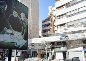 A billboard displaying an image of late Iranian Quds Force chief Qasem Soleimani (R) and Hezbolá leader Hassan Nasrallah (C) stands in front of a building targeted in an Israeli military strike on a Hezbolá commander in Beirut the previous day, on July 31, 2024 (ANWAR AMRO / AFP)
