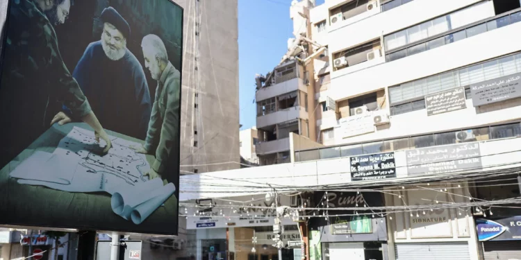 A billboard displaying an image of late Iranian Quds Force chief Qasem Soleimani (R) and Hezbolá leader Hassan Nasrallah (C) stands in front of a building targeted in an Israeli military strike on a Hezbolá commander in Beirut the previous day, on July 31, 2024 (ANWAR AMRO / AFP)