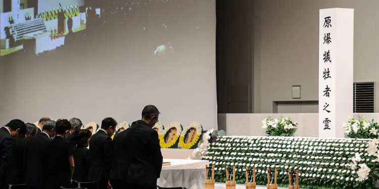 Los asistentes observan un momento de silencio en el momento del bombardeo atómico de 1945 a las 11:02 am mientras celebran una ceremonia en memoria de la paz en una instalación cubierta debido a la aproximación del tifón Khanun en Nagasaki, prefectura de Nagasaki, el 9 de agosto de 2023 (JIJI Press / AFP)