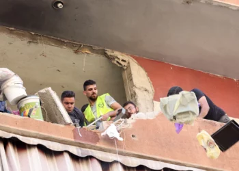 La gente retira los escombros de un edificio residencial cuyos dos pisos superiores fueron alcanzados por un ataque israelí contra la cabeza de la unidad de misiles de Hezbolá en el área de Ghobeiri, en los suburbios del sur de Beirut, el 24 de septiembre de 2024. (Foto de ANWAR AMRO / AFP)