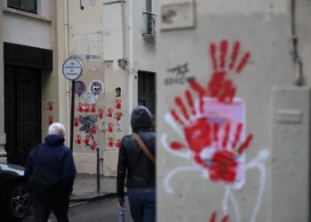 Una imagen muestra grafitis de manos rojas pintados en las paredes de los edificios de la calle Sainte-Croix de la Bretonnerie, en la zona donde anteriormente el monumento al Holocausto fue vandalizado con las mismas huellas de manos rojas en París, el 14 de mayo de 2024. (Antonin Utz/ AFP)