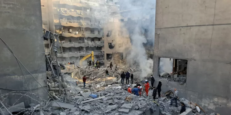 La gente se reúne mientras los rescatistas revisan los escombros de un edificio derribado, luego de un ataque aéreo israelí nocturno que tuvo como objetivo el barrio de Basta en Beirut el 23 de noviembre de 2024. (Fadel Itani/AFP)