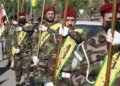 Los combatientes levantan banderas de Irak y de grupos paramilitares, incluidos Al Nujaba y Kataeb Hezbollah, durante un funeral en Bagdad por cinco terroristas muertos un día antes en un ataque estadounidense en el norte de Irak, el 4 de diciembre de 2023. (Ahmad Al-Rubaye/AFP)