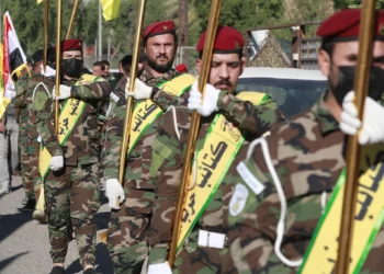 Los combatientes levantan banderas de Irak y de grupos paramilitares, incluidos Al Nujaba y Kataeb Hezbollah, durante un funeral en Bagdad por cinco terroristas muertos un día antes en un ataque estadounidense en el norte de Irak, el 4 de diciembre de 2023. (Ahmad Al-Rubaye/AFP)