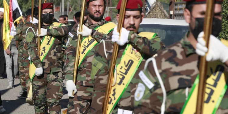 Los combatientes levantan banderas de Irak y de grupos paramilitares, incluidos Al Nujaba y Kataib Hezbolá, durante un funeral en Bagdad por cinco terroristas muertos un día antes en un ataque estadounidense en el norte de Irak, el 4 de diciembre de 2023. (Ahmad Al-Rubaye/AFP)