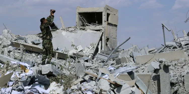 ARCHIVO: Un soldado sirio filma los daños causados ​​al Centro de Investigación Científica Sirio, que fue atacado por los militares estadounidenses, británicos y franceses, en Barzeh, cerca de Damasco, Siria, el 14 de abril de 2018. (AP/Hassan Ammar)