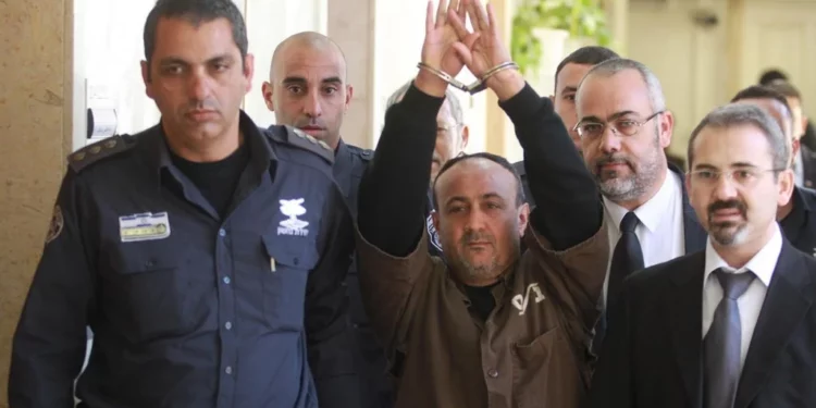 El jefe terrorista de Fatah, Marwan Barghouti, que cumple cinco cadenas perpetuas por asesinato durante la Segunda Intifada, es escoltado por la policía israelí hasta el Tribunal de Magistrados de Jerusalén para testificar como parte de una demanda civil estadounidense contra el liderazgo palestino, en enero de 2012. (Flash90)