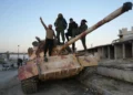 Combatientes antigubernamentales posan para una fotografía en un tanque en la carretera que conduce a Maaret al-Numan, en la provincia de Idlib, en el noroeste de Siria, el 30 de noviembre de 2024. (Muhammad Haj Kadour / AFP)