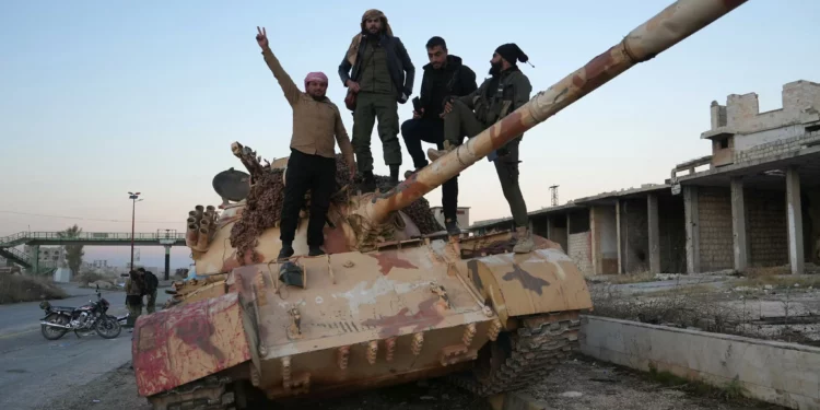 Combatientes antigubernamentales posan para una fotografía en un tanque en la carretera que conduce a Maaret al-Numan, en la provincia de Idlib, en el noroeste de Siria, el 30 de noviembre de 2024. (Muhammad Haj Kadour / AFP)