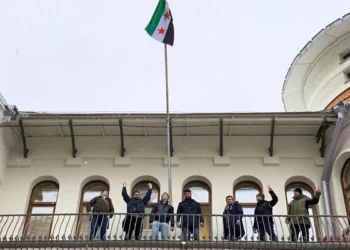 Los manifestantes reaccionan después de izar una bandera de la oposición siria en la embajada de Siria en Moscú el 9 de diciembre de 2024. (Foto de Andrey BORODULIN / AFP)