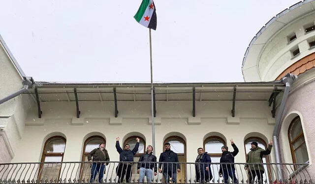 Los manifestantes reaccionan después de izar una bandera de la oposición siria en la embajada de Siria en Moscú el 9 de diciembre de 2024. (Foto de Andrey BORODULIN / AFP)