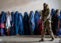 ARCHIVO - Un combatiente talibán hace guardia mientras las mujeres esperan recibir raciones de comida distribuidas por un grupo de ayuda humanitaria, en Kabul, Afganistán, el 23 de mayo de 2023. (Foto AP/Ebrahim Noroozi, Archivo)