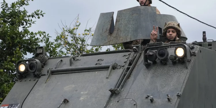 Un soldado del ejército libanés a bordo de un vehículo blindado de transporte de personal (APC) hace el signo de la victoria mientras un convoy ingresa a la aldea de Mansouri en su camino hacia el sur del Líbano, luego de un alto el fuego entre Israel y Hezbolá que entró en vigencia el miércoles 27 de noviembre de 2024. (Foto AP/Hussein Malla)