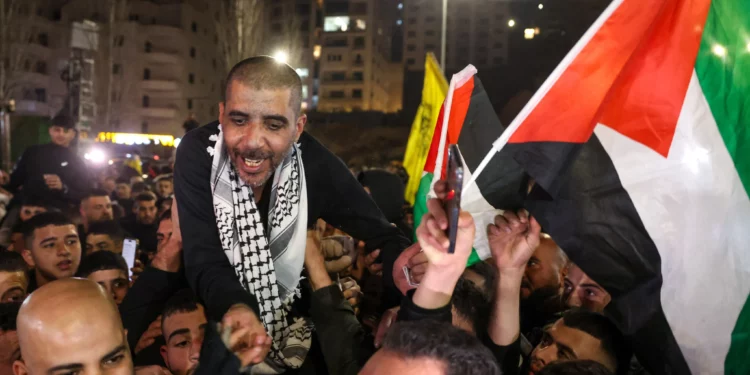 Zakaria Zubeidi, de 49 años, prisionero palestino y ex comandante de alto rango de las Brigadas de los Mártires de Al-Aqsa que fue liberado por Israel, ondea una bandera palestina mientras es vitoreado por la gente después de llegar a Ramallah a bordo de autobuses del Comité Internacional de la Cruz Roja (CICR), el 30 de enero de 2025. (AHMAD GHARABLI / AFP)