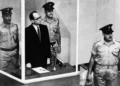 Adolf Eichmann de pie en su celda de cristal, flanqueado por guardias, en el tribunal de Jerusalén durante su juicio en 1961 por crímenes de guerra cometidos durante la Segunda Guerra Mundial. (Foto AP/Archivo)