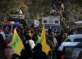 Soldados libaneses de pie en un vehículo rodeado de manifestantes que portan banderas de Hezbolá son vistos desde la ventana de un vehículo blindado de mantenimiento de la paz de la ONU, en la aldea de Mays al-Jabal, en el sur del Líbano, el 27 de enero de 2025. (Foto AP/Mohammad Zaatari)