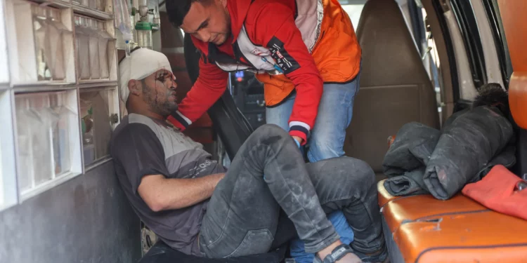 Un médico palestino ayuda a un hombre herido en ataques israelíes a desembarcar de una ambulancia en el hospital árabe Al-Ahli, también conocido como el hospital bautista, en la ciudad de Gaza el 13 de enero de 2025 (Foto de Omar AL-QATTAA / AFP)