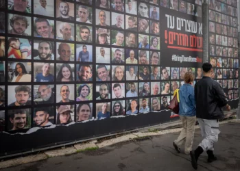 Personas caminando junto a fotografías de rehenes retenidos por terroristas de Hamás en Gaza, en Jerusalén, el 12 de enero de 2025 (Chaim Goldberg/Flash90