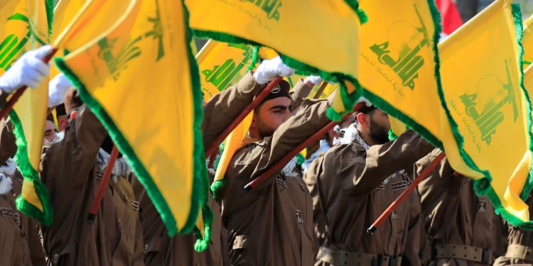 Miembros de Hezbolá levantan banderas del grupo terrorista libanés durante el funeral de un comandante y otro agente que murieron en un ataque con aviones no tripulados israelíes, en la aldea de Chehabiyeh, en el sur del Líbano, el 17 de abril de 2024. (Foto AP/Mohammed Zaatari)