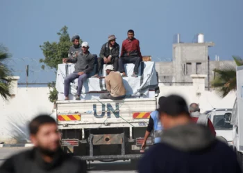 Los trabajadores se sientan en la parte trasera de un camión de la UNRWA durante una visita de un alto funcionario de emergencia de la agencia de la ONU para los refugiados palestinos (UNRWA) a Jan Yunis, en el sur de la Franja de Gaza, el 3 de diciembre de 2024. (BASHAR TALEB / AFP)