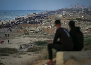 Dos niños observan a una multitud de palestinos que regresan al norte de Gaza, en medio de edificios destruidos, el 27 de enero de 2025. (AP/Abdel Kareem Hana)