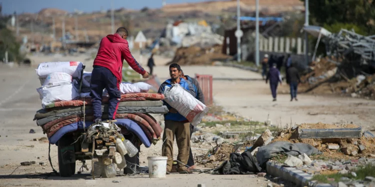 Palestinos desplazados cargan un carro con sus pertenencias cerca de un puesto de control en la calle Salah al-Din en Nuseirat el 25 de enero de 2025, mientras esperan regresar a sus hogares en la parte norte de la Franja de Gaza. Israel dijo el 25 de enero que bloquearía el regreso de los palestinos desplazados a sus hogares en el norte de Gaza hasta que la rehén civil Arbel Yehud sea liberada. (Foto de Eyad BABA / AFP)