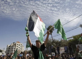 El terrorista de Hamás Nael Barghouti ondea una bandera islámica verde y una bandera palestina ante la multitud después de llegar a la ciudad de Ramallah, tras ser liberado como parte de un intercambio por Gilad Shalit, un soldado israelí retenido por Hamás, el 18 de octubre de 2011. (AP/Majdi Mohammed)