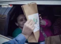 Esta imagen extraída de un video difundido por el grupo terrorista Hamás muestra a las rehenes israelíes Emily Damari (izq.) y Romi Gonen, recibiendo un paquete con el logo del brazo armado de Hamás, mientras están sentadas en un vehículo de Hamás antes de ser entregadas al Comité Internacional de la Cruz Roja en la Franja de Gaza el 19 de enero de 2025. (Captura de pantalla: Hamás/AFP)