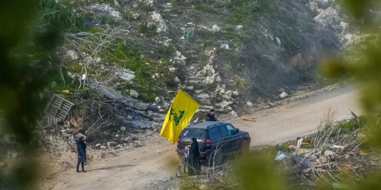 Libaneses ondean una bandera de Hezbolá en el sur del Líbano, vista desde el lado israelí de la frontera, el 18 de febrero de 2025 (Ayal Margolin/Flash90)