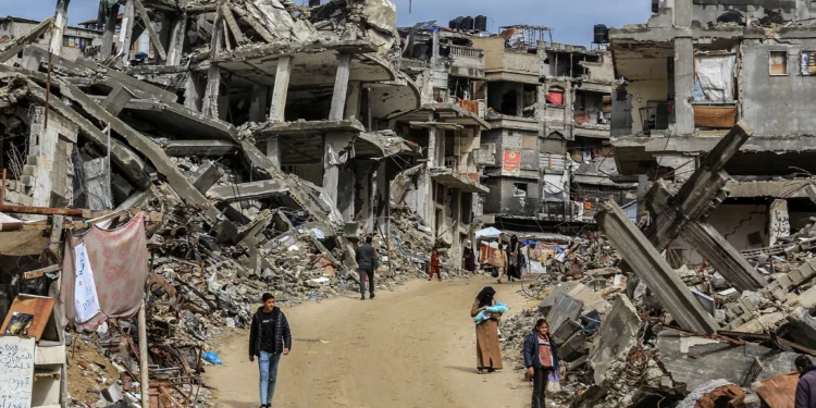 Los palestinos deambulan entre los escombros de sus casas, destruidas en la guerra entre Israel y Hamás, en la ciudad de Jan Yunis, en el sur de la Franja de Gaza, el 23 de febrero de 2025. (Abed Rahim Khatib/Flash90)