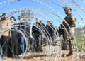 La gente se alinea detrás del alambre de púas instalado por el ejército libanés mientras se preparan para ingresar a la aldea de Adaisseh, en el sur del Líbano, el 18 de febrero de 2025, luego de la retirada de las tropas israelíes (Foto de Mahmoud ZAYAT / AFP)