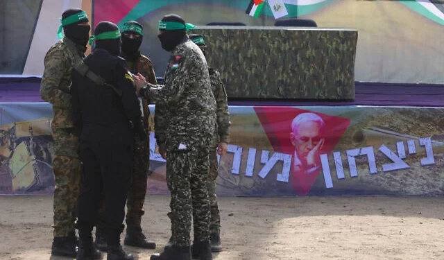 Hombres armados de Hamás se encuentran frente a un escenario antes de entregar a tres rehenes israelíes a un equipo de la Cruz Roja en Deir el-Balah, en el centro de Gaza, el 8 de febrero de 2025. (BASHAR TALEB / AFP)