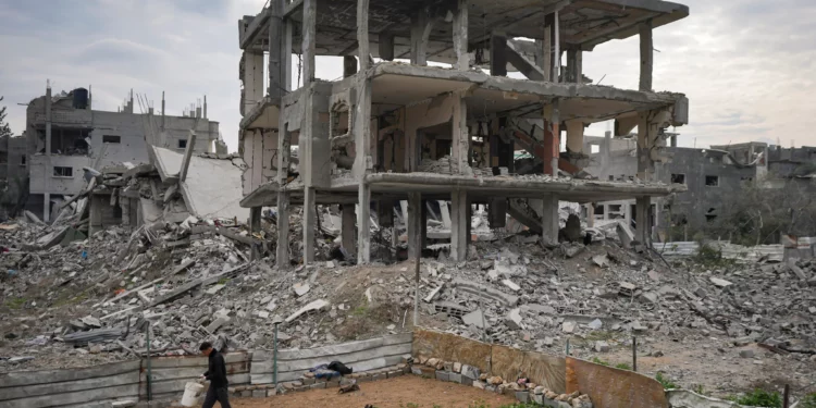 Un palestino camina junto a edificios residenciales destruidos por la ofensiva aérea y terrestre israelí en Bureij, en el centro de la Franja de Gaza, el 22 de enero de 2025. (Foto AP/Abdel Kareem Hana)