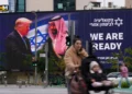 La gente pasa frente a un cartel electrónico que muestra al presidente de Estados Unidos, Donald Trump, a la izquierda, estrechando la mano del príncipe heredero saudí, Mohammed bin Salman, con un texto que dice: "Estamos listos", en Tel Aviv, el 3 de febrero de 2025. (Foto AP/ Ariel Schalit)