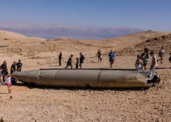 Israelíes observan los restos de un misil iraní, en el desierto de Negev, cerca de Arad, el 3 de octubre de 2024. (MENAHEM KAHANA / AFP)