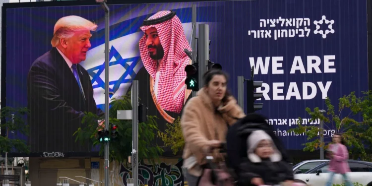 La gente pasa frente a un cartel electrónico que muestra al presidente de Estados Unidos, Donald Trump, a la izquierda, estrechando la mano del príncipe heredero saudí, Mohammed bin Salman, con el mensaje a favor de la normalización "Estamos listos", en Tel Aviv, el 3 de febrero de 2025. (Foto AP/ Ariel Schalit)