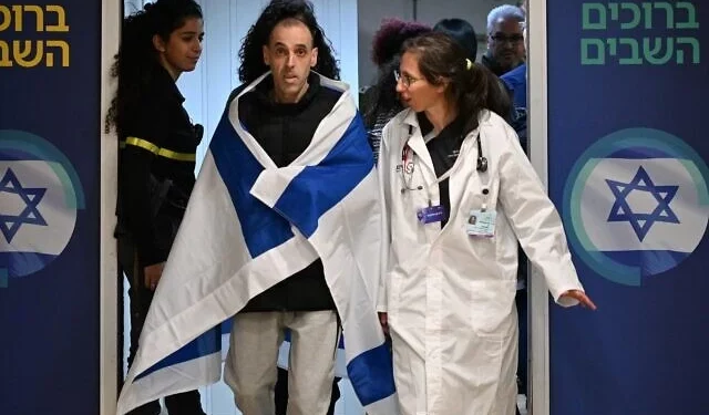 El rehén liberado Eli Sharabi llega al Centro Médico Sheba cerca de Tel Aviv, envuelto en una bandera israelí, mientras camina para reunirse con miembros de su familia después de 491 días de cautiverio en Hamás, el 8 de febrero de 2025. (Haim Tsach/GPO)