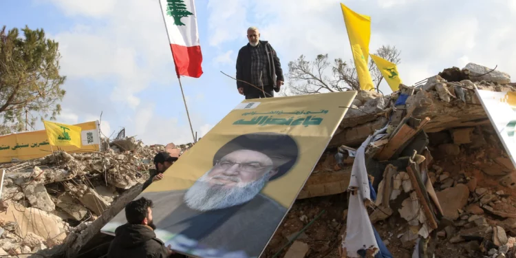 La gente coloca una imagen del líder asesinado de Hezbolá, Hassan Nasrallah, sobre los escombros del santuario de Shamoun al-Safa, en el pueblo de Shamaa, en Tiro, en el sur del Líbano, el 31 de enero de 2025. (Mahmoud ZAYYAT / AFP)